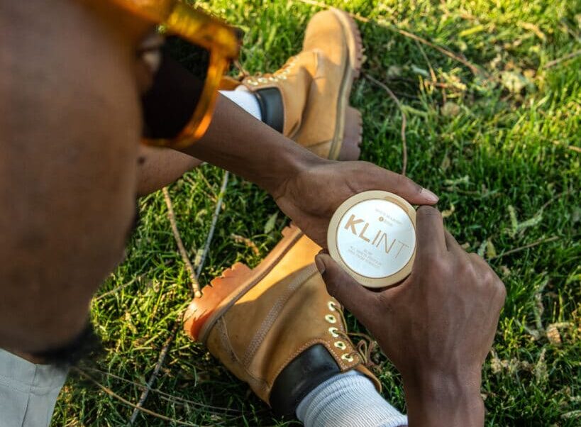 what are nicotine pouches? man holding nic pouches sat on grass